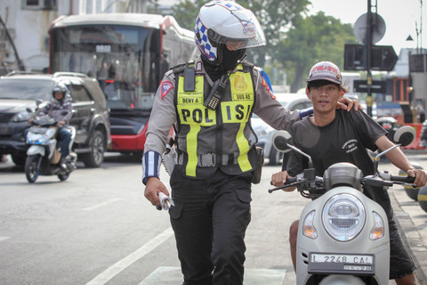 Seorang anggota Satlantas Polrestabes Surabaya menghentikan pengendara motor yang terjaring saat Operasi Patuh Semeru 2024 di Jalan Rajawali, Surabaya, Jawa Timur, Selasa (16/7/2024). Foto: Didik Suhartono/ANTARA FOTO