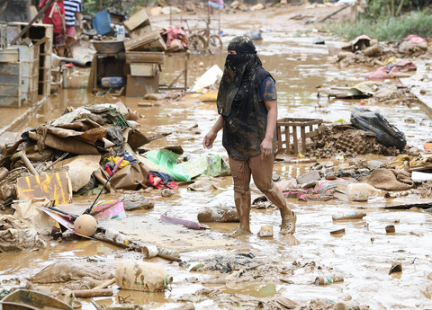 Seorang warga berjalan di antara puing-puing barang-barang yang hancur di samping rumahnya di sebuah desa di Manila, Kamis (25/7/2024). Foto: Ted Aljibe/AFP