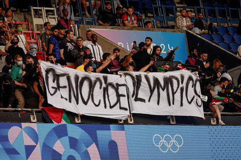 Penonton memegang spanduk bertuliskan "Olimpiade Genosida" saat pertandingan grup D Olimpiade Paris 2024 antara Israel dan Paraguay di Parc des Princes, Paris, Prancis, Sabtu (27/7/2024). Foto: Aurelien Morissard/AP Photo