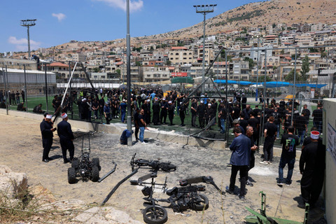 Anggota komunitas Druze melihat pagar yang rusak dan benda-benda yang berserakan di lapangan sepak bola, sehari setelah 12 orang terbunuh di sana dalam serangan roket dari Lebanon di kota Druze Majdal Shams di Dataran Tinggi Golan, Minggu (28/7/2024) Foto: MENAHEM KAHANA / AFP