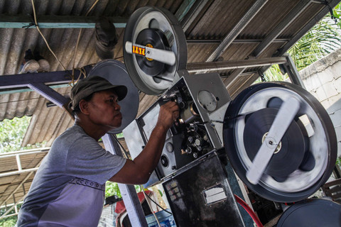 Penyedia jasa layanan penyewaan film untuk layar tancap Nur Iyan melakukan perawatan film seluloid 35 milimeter (mm) koleksinya di kawasan Pamulang, Tangerang Selatan, Banten, Senin (29/7/2024). Foto: Darryl Ramadhan/kumparan