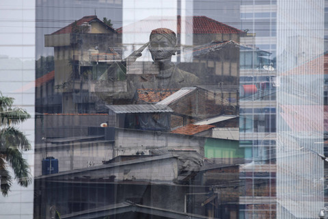 Foto dengan teknik Multiple Exposure antara patung Jenderal Sudirman dengan permukiman di Jakarta. Foto: Syawal Darisman/kumparan