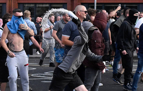 Seorang pengunjuk rasa bertopeng melemparkan kaleng ke arah polisi saat bentrokan terjadi di Bristol, Inggris, Sabtu (3/8/2024). Foto: Justin TALLIS / AFP