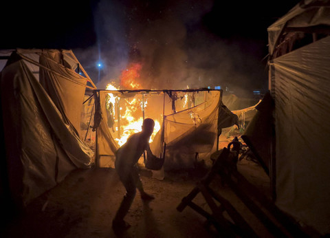 Warga Palestina berusaha memadamkan api di lokasi serangan Israel di sebuah kamp tenda untuk para pengungsi, di tengah konflik Israel-Hamas, di Deir Al-Balah di Jalur Gaza tengah, Minggu (4/8/2024). Foto: Abdullah Al-Attar/REUTERS