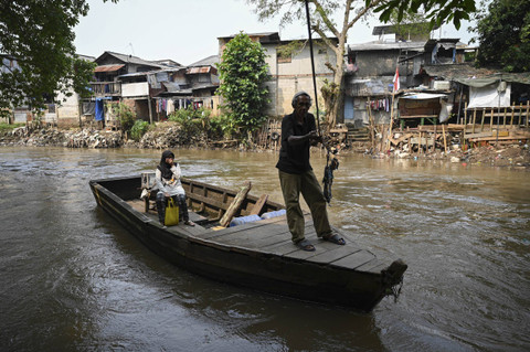 Warga menyeberangi sungai menggunakan perahu eretan di kawasan Manggarai, Jakarta, Senin (5/8/2024). Foto: Fauzan/ANTARA FOTO