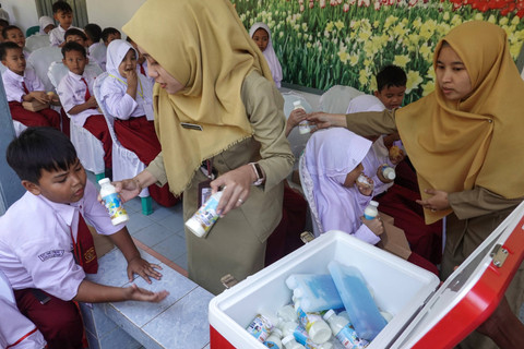 Dua orang guru membagikan susu sapi murni kepada siswa SD Negeri 1 Sudagaran, Banyumas, Jawa Tengah, Senin (5/8/2024). Foto: Idhad Zakaria/ANTARA FOTO