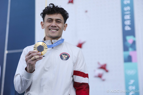 Atlet panjat tebing putra Indonesia peraih medali emas Veddriq Leonardo  mengangkat medali emasnya di podium seusai penyerahan medali final nomor speed putra Olimpiade Paris 2024, Kamis (8/8/2024). Foto: Dok. NOC Indonesia 