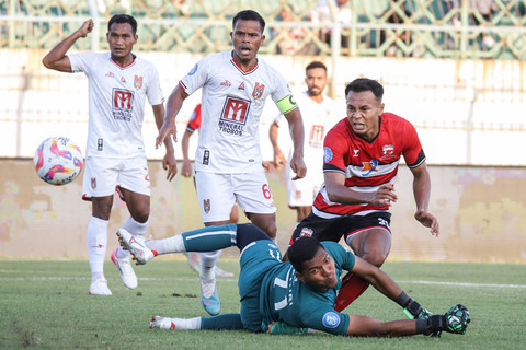 Pesepak bola Madura United Koko Ari Araya (kanan) menendang bola yang berusaha dihadang kiper Malut United M Fahri (kedua kanan) pada pertandingan BRI Liga 1 di Stadion Gelora Bangkalan, Bangkalan, Jawa Timur, Sabtu (10/8/2024). Foto: ANTARA FOTO/Rizal Hanafi