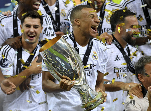 Penyerang Real Madrid Kylian Mbappe merayakan dengan trofi setelah pertandingan sepak bola Piala Super Eropa antara Real Madrid dan Atalanta BC di Warsawa, Kamis (15/8/2024). Foto: Sergei Gapon/AFP