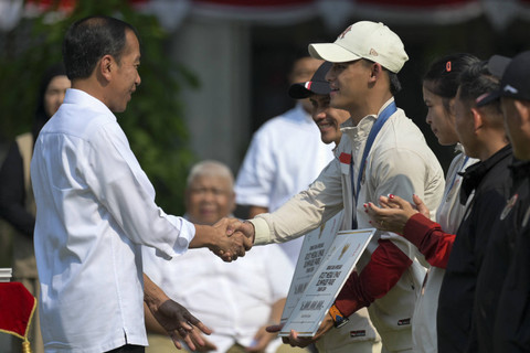 Presiden Joko Widodo (kiri) memberikan bonus kepada Lifter putra peraih medali emas Olimpiade Paris 2024 Rizki Juniansyah (kedua kiri) di halaman Istana Merdeka, Jakarta, Kamis (15/8/2024). Foto: Bay Ismoyo/AFP
