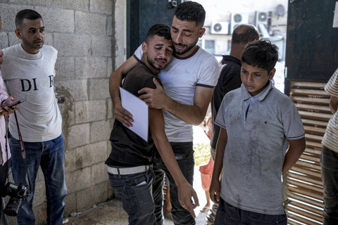 Warga Palestina berduka atas saudara kembar mereka yang tewas dalam pemboman Israel di Jalur Gaza, sambil memegang akta kelahiran mereka, di kamar mayat rumah sakit di Deir al-Balah, Selasa, 13 Agustus 2024. Foto: AP Foto/Abdel Kareem Hana