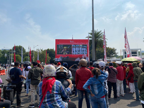 Sejumlah warga menonton upacara HUT ke-79 RI melalui layar kaca di depan Monumen Nasional (Monas), Jakarta, Sabtu (17/8/2024).  Foto: Abid Raihan/kumparan