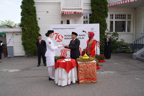Dubes RI untuk Norwegia dan Islandia, Teuku Faizasyah memberikan potongan tumpeng kepada salah satu pengibar bendera saat perayaan HUT RI di Oslo, Sabtu (17/8/2024). Foto: Dok. Istimewa