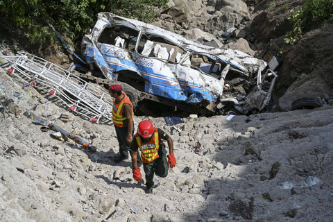 Petugas penyelamat memeriksa bangkai sebuah bus yang terlihat di lokasi kecelakaan di provinsi Punjab, Pakistan, Minggu (25/8/2024). Foto: Aamir QURESHI/AFP