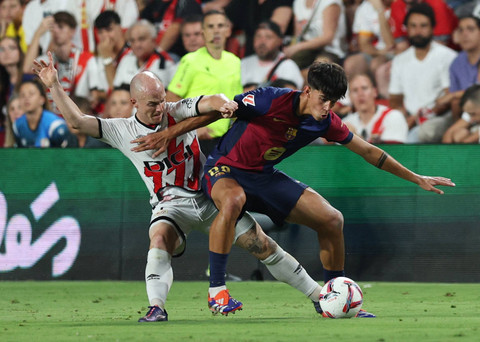 Duel Isi Palazon dengan Marc Bernal saat Rayo Vallecano vs Barcelona dalam laga pekan ketiga Liga Spanyol 2024/25 di Estadio de Vallecas, Rabu (28/8) dini hari WIB. Foto: REUTERS/Violeta Santos Moura