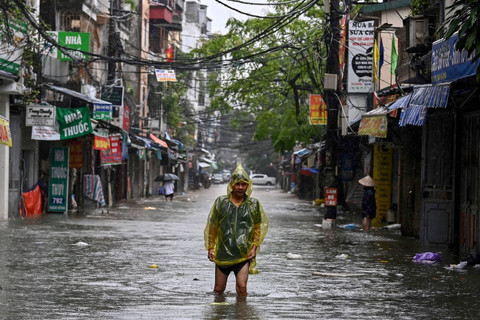 Warga berjalan melewati banjir imbas Topan Yagi di Hanoi, Vietnam, Rabu (11/9/2024). Foto: Nhac NGUYEN / AFP