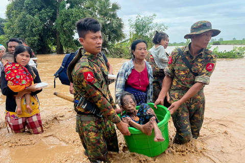 Warga dibantu melewati banjir oleh personel militer di Pyinmana di wilayah Naypyidaw, Myanmar, pada 13 September 2024, menyusul hujan lebat setelah Topan Yagi. Foto: Sai Aung MAIN / AFP