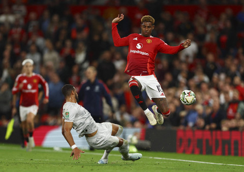 Marcus Rashford dari Manchester United beraksi dengan pemain Barnsley, Barry Cotter pada pertandingan Piala Carabao antara Manchester United vs Barnsley di Old Trafford, Manchester, Inggris, Rabu (18/9/2024). Foto: Molly Darlington/REUTERS