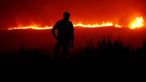 Seorang pria berdiri di sekitar kebakaran hutan, dekat Povoa de Montemuro, Portugal, 18 September 2024. Foto: REUTERS/Susana Vera