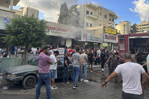 Orang-orang berkumpul ketika petugas pemadam kebakaran memadamkan api di lokasi ledakan bom yang dilaporkan di Saida, Lebanon selatan, Rabu (18/9/2024). Foto: Anwar Amro/AFP