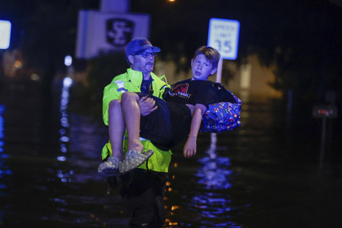 Petugas Pemadam Kebakaran Citrus County membawa anak berusia 11 tahun, Michael Cribbins, saat melakukan penyelamatan dari banjir setelah Badai Helene pada hari Jumat, 27 September 2024 di Crystal River, Florida. Foto: AP Photo/Mike Carlson
