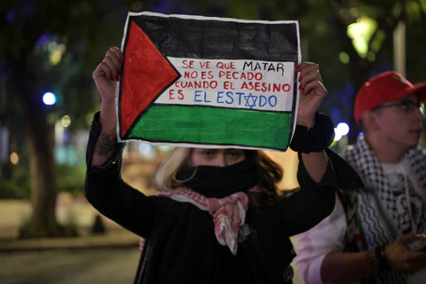 Seorang aktivis pro-Palestina membentangkan poster saat mengikuti aksi peringatan satu tahun konflik Israel-Hamas di Meksiko, Senin (7/10/2024). Foto: YURI CORTEZ/AFP