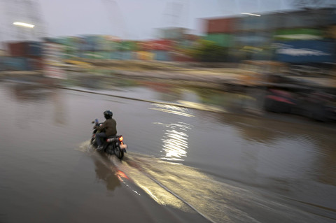 Seorang warga menggunakan kendaraan roda dua melintas di tengah banjir rob di Pelabuhan Sunda Kelapa, Jakarta, Rabu (9/10/2024). Foto: Fauzan/ANTARA FOTO