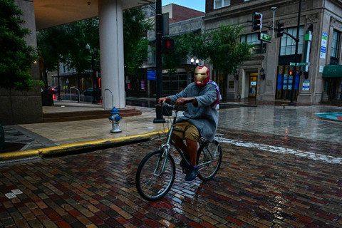 Seorang pria mengendarai sepeda dengan mengenakan topeng Ironman di pusat kota Orlando, Florida, saat Badai Milton diperkirakan akan mendarat malam ini, 9 Oktober 2024. Foto: Giorgio VIERA/AFP