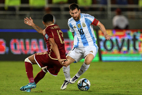 Pemain Argentina Lionel Messi berusaha melewati pemain Venezuela Jose Martinez dalam pertandingan kualifikasi Piala Dunia 2026 zona CONMEBOL di Stadion Monumental de Maturin, Venezuela, Jumat (10/10/2024). Foto: Juan BARRETO/AFP
