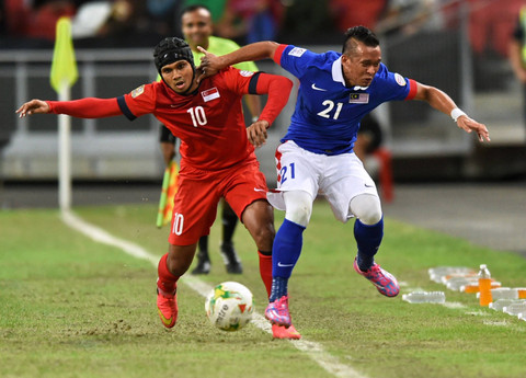 Pemain Malaysia Zubir Azmi (R) dan pemain Singapura Fazrul Nawaz (L) berebut bola dalam pertandingan sepak bola Piala AFF Suzuki 2014 di stadion Nasional, Singapura, pada 29 November 2014. Foto: Roslan Rahman/AFP