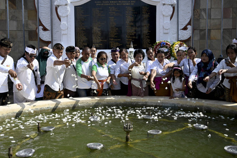 Sejumlah warga menabur bunga ke tugu peringatan bom Bali 2002 saat upacara peringatan peringatan ke-22 bom Bali di Tugu Peringatan Bom Bali, Kuta, Bali, Sabtu (12/10/2024). Foto: Sonny Tumbelaka/AFP