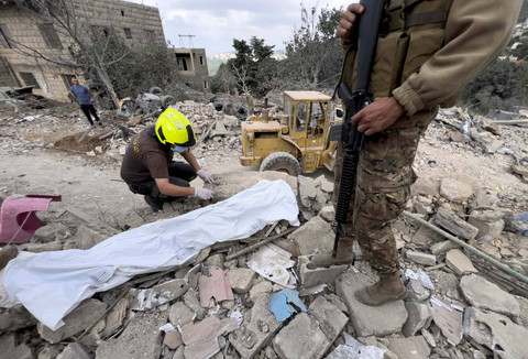 Seorang pekerja Pertahanan Sipil mencari sisa-sisa jenazah di antara puing-puing bangunan yang hancur di lokasi serangan udara Israel hari Senin di desa Aito, Lebanon utara, Selasa (15/10/2024). Foto: Hussein Malla/AP PHOTO