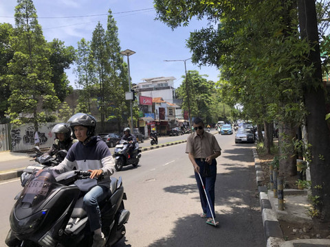 Seorang tunanetra yang berjalan kaki tidak di trotoar, Rabu (16/10/2024). Foto: Robby Bouceu/kumparan