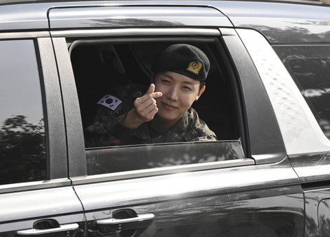 Anggota BTS, J-hope, memberi isyarat kepada para penggemar saat ia pergi setelah keluar dari wajib militer di luar pangkalan militer di Wonju pada 17 Oktober 2024. Foto: Jung Yeon-je/AFP