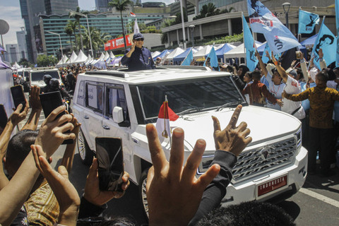 Presiden Prabowo Subianto berdiri menyapa warga dari mobil Pindad Maung Garuda di Jalan MH. Thamrin, Jakarta, Minggu (20/10/2024). Foto: Sigid Kurniawan/ANTARA FOTO