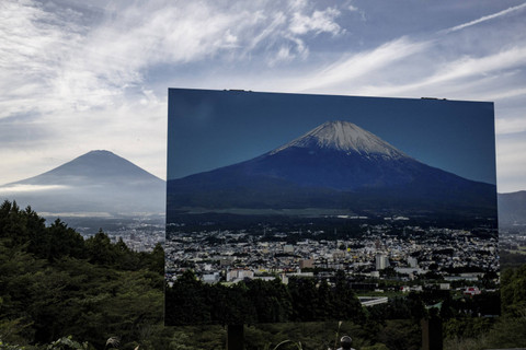Sebuah tanda dengan foto Gunung Fuji yang diselimuti salju terlihat di sebuah titik pandang saat Gunung Fuji, gunung tertinggi di Jepang setinggi 3.776 meter, tampak di latar belakang di Gotemba, prefektur Shizuoka pada tanggal 31 Oktober 2024. Foto: YUICHI YAMAZAKI/AFP