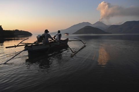 Nelayan berangkat mencari ikan dengan latar belakang Gunung Lewotobi Laki-Laki yang mengeluarkan kolom asap, Senin (11/11/2024). Foto: Aditya Pradana Putra/ANTARA FOTO