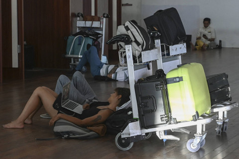 Para penumpang yang penerbangannya dibatalkan menunggu di Bandara Internasional Ngurah Rai, Denpasar, Bali, Rabu (13/11/2024). Foto: Sonny Tumbelaka/AFP