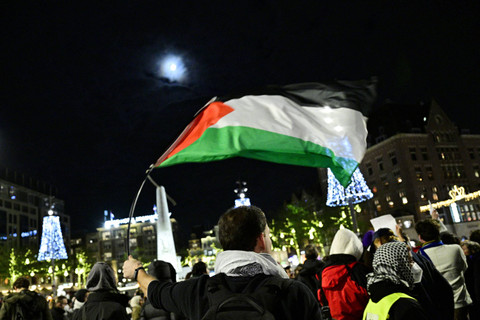 Seorang pengunjuk rasa mengibarkan bendera Palestina dalam sebuah demonstrasi pro-Palestina yang tidak sah di Dam Square di Amsterdam, Belanda, Rabu (13/11/2024) waktu setempat. Foto: NICK GAMMON/AFP