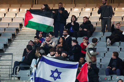 Seorang penggemar mengibarkan bendera Palestina dan Israel saat menghadiri pertandingan Prancis melawan Israel pada laga lanjutan UEFA Nations League di Stade de France, Saint-Denis, Prancis, Kamis (14/11/2024). Foto: Gonzalo Fuentes/REUTERS