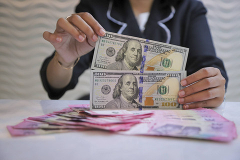 Seorang petugas menunjukan pecahan Dolar AS dan Rupiah di kawasan Kwitang, Jakarta, Senin (18/11/2024). Foto: Iqbal Firdaus/kumparan