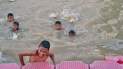 Keseruan Anak-anak yang mandi di sùngai kawasan Jalan Merdeka, Palembang yang memanfaatkan luapan air kala musim hujan, Sabtu (23/11) Foto: ary priyanto/urbn id