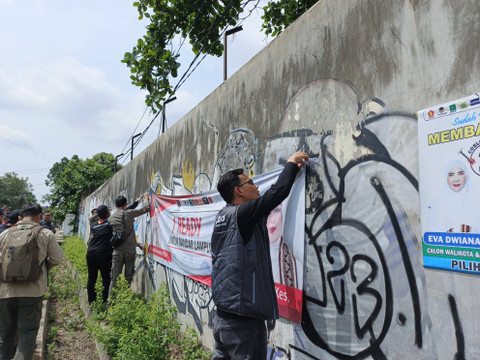 Anggota Bawaslu Kota Bandar Lampung, Muhamad Muhyi saat melakukan pembersihan alat peraga kampanye (APK) di Kecamatan Sukarame, Bandar Lampung | Foto : Eka Febriani / Lampung Geh