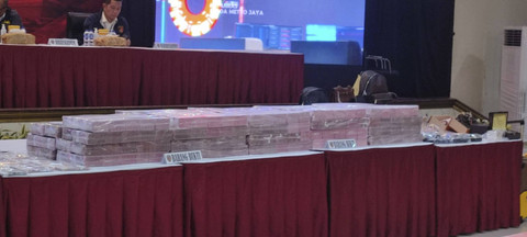 Tumpukan uang tunai dan lukisan yang disita polisi terkait kasus judi online yang melibatkan pegawai Komdigi. Foto: Rachmadi Rasyad/kumparan