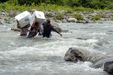 Personel kepolisian bersama petugas Bawaslu menyeberangi Sungai Tompobulu untuk mendistribusikan logistik Pilkada 2024 ke Dusun Makmur, Desa Bonto Manurung, Kecamatan Tompobulu, Kabupaten Maros, Sulawesi Selatan, Selasa (26/11/2024). Foto: Hasrul Said/ANTARA FOTO