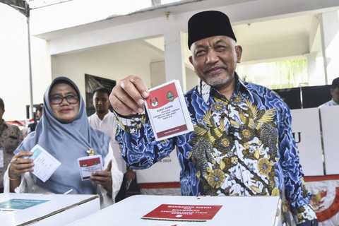 Calon Gubernur Jawa Barat nomor urut tiga Ahmad Syaikhu (kanan) bersama istrinya Lilik Wakhidah (kiri) menunjukkan surat suara usai menggunakan hak pilih di Tempat Pemungutan Suara (TPS) 080, Pondok Gede, Bekasi, Jawa Barat, Rabu (27/11/2024). Foto: Fakhri Hermansyah/ANTARA FOTO