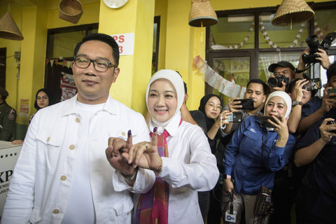 Calon gubernur DKI Jakarta nomor urut 1 Ridwan Kamil bersama istri sekaligus Anggota Komisi VIII DPR RI Atalia Praratya menunjukkan tinta di jarinya usai menggunakan hak pilihnya pada pilkada 2024 di TPS 23, Bandung, Rabu (27/11/2024). Foto: Novrian Arbi/ANTARA FOTO