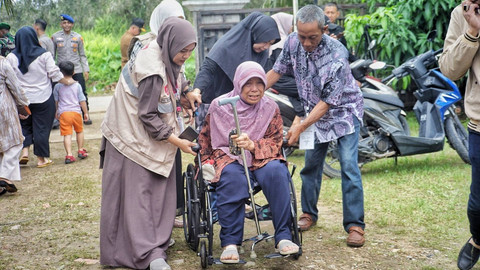 Tim kesehatan di TPS 25 menolong seorang warga yang hendak melakukan pencoblosan surat suara dalam proses pilkda yang digelar di Kota Palembang, Rabu (27/11) Foto: ary priyanto/urban id