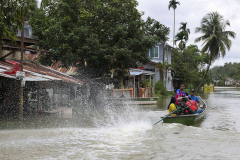 Penduduk setempat menggunakan perahu untuk menyeberangi jalanan yang tergenang banjir di Pasir Mas, negara bagian Kelantan, Malaysia, pada tanggal 21 Desember 2022. Foto: STR/AFP