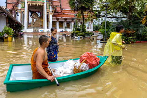 Seorang biksu Buddha dan penduduk setempat berjalan melalui jalan yang banjir di Kuil Wat Mahattamankalaram di distrik Hat Yai, provinsi Songkhla, Thailand, Sabtu (30/1/2024). Foto: Roylee Suriyaworakul/REUTERS